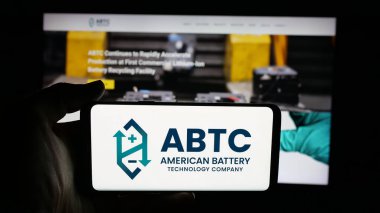 Stuttgart, Germany - 11-04-2025: Person holding cellphone with logo of American Battery Technology Company (ABTC) on screen in front of webpage. Focus on phone display.