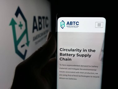 Stuttgart, Germany - 11-04-2025: Person holding cellphone with webpage of American Battery Technology Company (ABTC) on screen in front of logo. Focus on center of phone display.