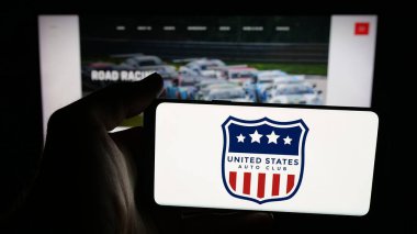 Stuttgart, Germany - 11-04-2025: Person holding mobile phone with logo of organisation United States Auto Club (USAC) on screen in front of web page. Focus on phone display.
