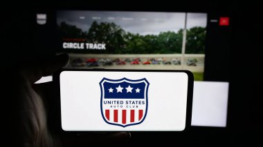 Stuttgart, Germany - 11-04-2025: Person holding cellphone with logo of organisation United States Auto Club (USAC) on screen in front of webpage. Focus on phone display.