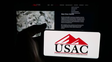 Stuttgart, Germany - 11-04-2025: Person holding mobile phone with logo of US company United States Antimony Corporation on screen in front of web page. Focus on phone display.