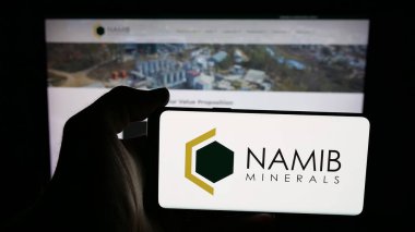 Stuttgart, Germany - 11-04-2025: Person holding mobile phone with logo of gold mining company Namib Minerals on screen in front of web page. Focus on phone display.