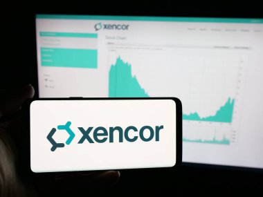 Stuttgart, Germany - 11-04-2025: Person holding smartphone with logo of US biotechnology company Xencor Inc. on screen in front of website. Focus on phone display.