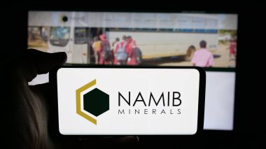 Stuttgart, Germany - 11-04-2025: Person holding cellphone with logo of gold mining company Namib Minerals on screen in front of webpage. Focus on phone display.