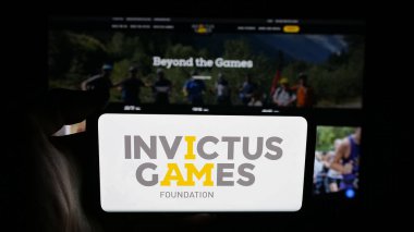 Stuttgart, Germany - 11-05-2025: Person holding cellphone with logo of international sport event Invictus Games on screen in front of webpage. Focus on phone display.