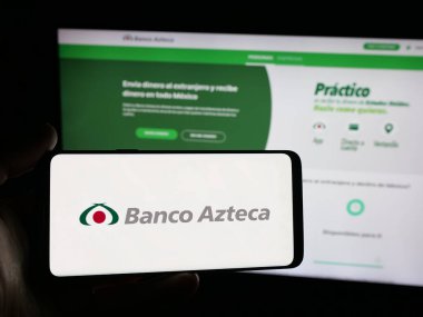 Stuttgart, Germany - 11-05-2025: Person holding smartphone with logo of Mexican financial company Banco Azteca on screen in front of website. Focus on phone display.