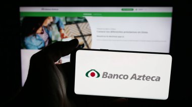 Stuttgart, Germany - 11-05-2025: Person holding mobile phone with logo of Mexican financial company Banco Azteca on screen in front of web page. Focus on phone display.