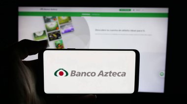 Stuttgart, Germany - 11-05-2025: Person holding cellphone with logo of Mexican financial company Banco Azteca on screen in front of webpage. Focus on phone display.