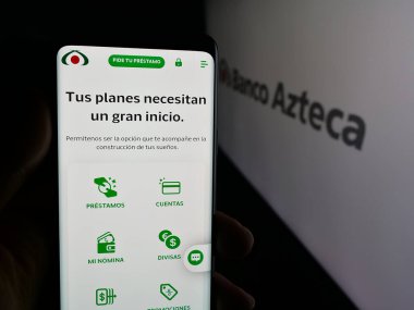Stuttgart, Germany - 11-05-2025: Person holding cellphone with webpage of Mexican financial company Banco Azteca on screen in front of logo. Focus on center of phone display.