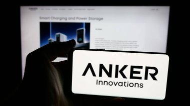 Stuttgart, Germany - 11-05-2025: Person holding mobile phone with logo of Chinese company Anker Innovations Co. Ltd. on screen in front of web page. Focus on phone display.
