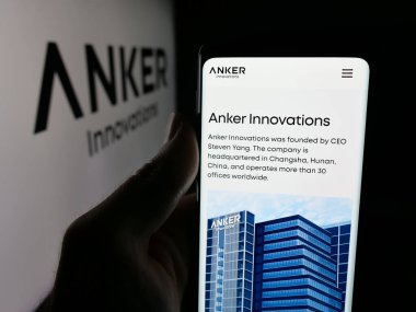 Stuttgart, Germany - 11-05-2025: Person holding cellphone with webpage of Chinese company Anker Innovations Co. Ltd. on screen in front of logo. Focus on center of phone display.