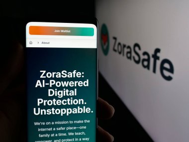 Stuttgart, Germany - 11-05-2025: Person holding smartphone with web page of US AI cybersecurity company ZoraSafe Inc. on screen in front of logo. Focus on center of phone display.
