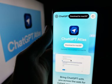 Stuttgart, Germany - 11-05-2025: Person holding smartphone with web page of AI browser ChatGPT Atlas (OpenAI) on screen in front of logo. Focus on center of phone display.