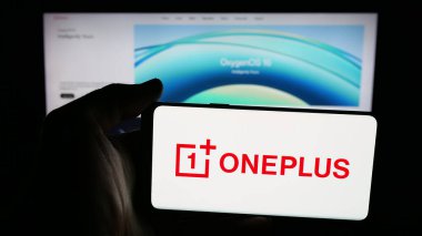 Stuttgart, Germany - 11-05-2025: Person holding mobile phone with logo of company OnePlus Technology (Shenzhen) Co. Ltd on screen in front of web page. Focus on phone display.