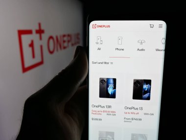 Stuttgart, Germany - 11-05-2025: Person holding smartphone with web page of company OnePlus Technology (Shenzhen) Co. Ltd on screen in front of logo. Focus on center of phone display.
