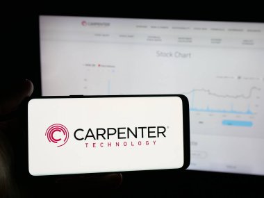 Stuttgart, Germany - 11-05-2025: Person holding smartphone with logo of US company Carpenter Technology Corporation on screen in front of website. Focus on phone display.