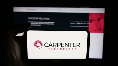 Stuttgart, Germany - 11-05-2025: Person holding cellphone with logo of US company Carpenter Technology Corporation on screen in front of webpage. Focus on phone display.