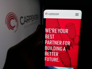 Stuttgart, Germany - 11-05-2025: Person holding smartphone with web page of US company Carpenter Technology Corporation on screen in front of logo. Focus on center of phone display.