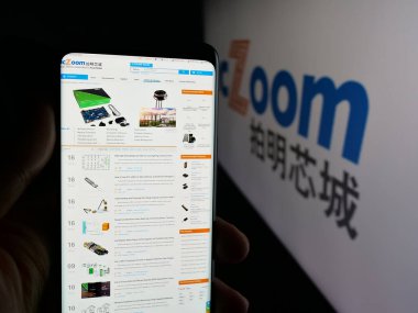 Stuttgart, Germany - 11-06-2025: Person holding cellphone with webpage of Chinese electronics company ICZOOM Group Inc. on screen in front of logo. Focus on center of phone display.