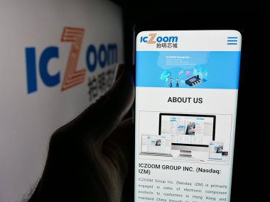Stuttgart, Germany - 11-06-2025: Person holding smartphone with web page of Chinese electronics company ICZOOM Group Inc. on screen in front of logo. Focus on center of phone display.