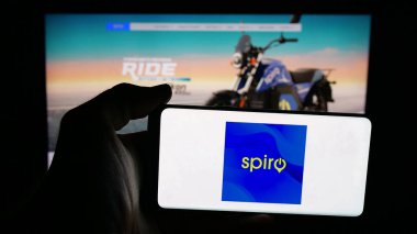 Stuttgart, Germany - 11-06-2025: Person holding mobile phone with logo of Kenyan electric vehicle company Spiro on screen in front of web page. Focus on phone display.