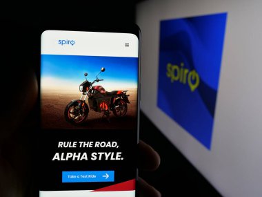 Stuttgart, Germany - 11-06-2025: Person holding cellphone with webpage of Kenyan electric vehicle company Spiro on screen in front of logo. Focus on center of phone display.