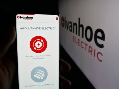 Stuttgart, Germany - 11-06-2025: Person holding smartphone with web page of US minerals company Ivanhoe Electric Inc. on screen in front of logo. Focus on center of phone display.