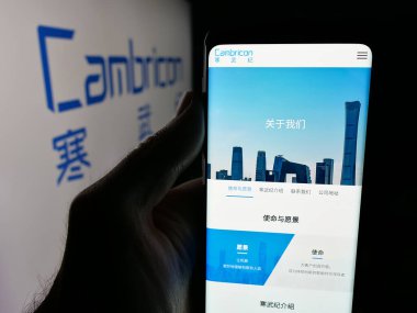 Stuttgart, Germany - 11-06-2025: Person holding smartphone with web page of semiconductor company Cambricon Technologies on screen in front of logo. Focus on center of phone display.