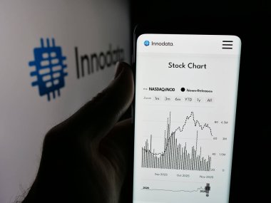 Stuttgart, Germany - 11-06-2025: Person holding smartphone with web page of information technology company Innodata Inc. on screen in front of logo. Focus on center of phone display.