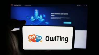 Stuttgart, Germany - 11-06-2025: Person holding cellphone with logo of blockchain technology company OwlTing Group on screen in front of webpage. Focus on phone display.