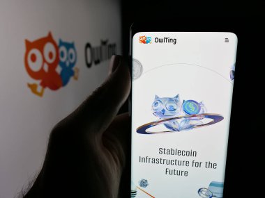 Stuttgart, Germany - 11-06-2025: Person holding smartphone with web page of blockchain technology company OwlTing Group on screen in front of logo. Focus on center of phone display.