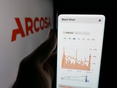 Stuttgart, Germany - 11-07-2025: Person holding smartphone with web page of US infrastructure company Arcosa Inc. on screen in front of logo. Focus on center of phone display.