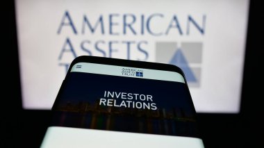 Stuttgart, Germany - 11-07-2025: Mobile phone with website of US REIT company American Assets Trust Inc. on screen in front of logo. Focus on top-left of phone display.