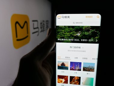 Stuttgart, Germany - 11-07-2025: Person holding cellphone with webpage of Chinese travel company Mafengwo.com on screen in front of logo. Focus on center of phone display.