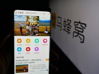 Stuttgart, Germany - 11-07-2025: Person holding smartphone with web page of Chinese travel company Mafengwo.com on screen in front of logo. Focus on center of phone display.