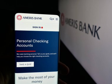 Stuttgart, Germany - 11-07-2025: Person holding smartphone with web page of US financial services company Ameris Bank on screen in front of logo. Focus on center of phone display.