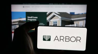 Stuttgart, Germany - 11-07-2025: Person holding mobile phone with logo of US REIT company Arbor Realty Trust Inc. on screen in front of web page. Focus on phone display.