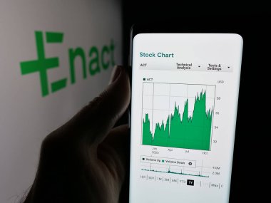 Stuttgart, Germany - 11-07-2025: Person holding smartphone with web page of US mortgage company Enact Holdings Inc. on screen in front of logo. Focus on center of phone display.