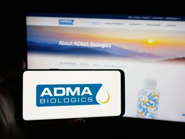 Stuttgart, Germany - 11-07-2025: Person holding smartphone with logo of US biopharma company ADMA Biologics Inc. on screen in front of website. Focus on phone display.