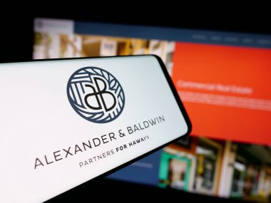 Stuttgart, Germany - 11-08-2025: Smartphone with logo of Hawaiian company Alexander Baldwin Inc. on screen in front of website. Focus on center-left of phone display.