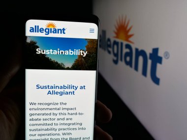 Stuttgart, Germany - 11-08-2025: Person holding cellphone with webpage of US airline business Allegiant Travel Company on screen in front of logo. Focus on center of phone display.