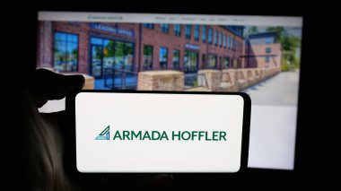 Stuttgart, Germany - 11-08-2025: Person holding cellphone with logo of US company Armada Hoffler Properties Inc. on screen in front of webpage. Focus on phone display.