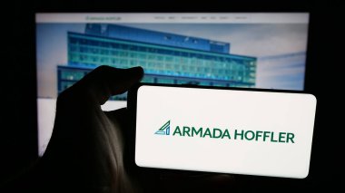 Stuttgart, Germany - 11-08-2025: Person holding mobile phone with logo of US company Armada Hoffler Properties Inc. on screen in front of web page. Focus on phone display.