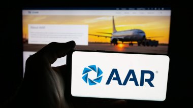 Stuttgart, Germany - 11-08-2025: Person holding mobile phone with logo of US aircraft maintenance company AAR Corp. on screen in front of web page. Focus on phone display.
