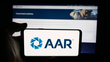 Stuttgart, Germany - 11-08-2025: Person holding cellphone with logo of US aircraft maintenance company AAR Corp. on screen in front of webpage. Focus on phone display.