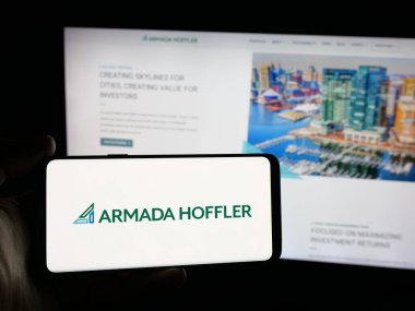 Stuttgart, Germany - 11-08-2025: Person holding smartphone with logo of US company Armada Hoffler Properties Inc. on screen in front of website. Focus on phone display.