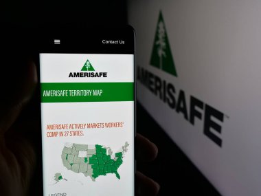 Stuttgart, Germany - 11-08-2025: Person holding smartphone with web page of US insurance company Amerisafe Inc. on screen in front of logo. Focus on center of phone display.