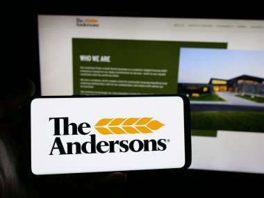 Stuttgart, Germany - 11-08-2025: Person holding smartphone with logo of US agribusiness company The Andersons Inc. on screen in front of website. Focus on phone display.