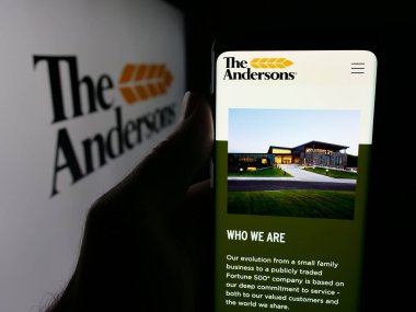 Stuttgart, Germany - 11-08-2025: Person holding smartphone with web page of US agribusiness company The Andersons Inc. on screen in front of logo. Focus on center of phone display.