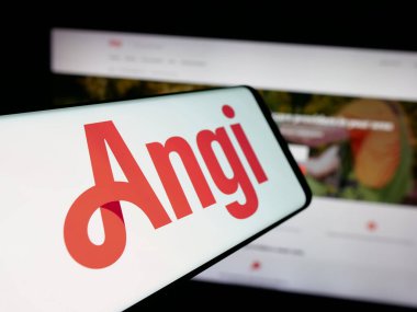 Stuttgart, Germany - 11-08-2025: Smartphone with logo of US online marketplace company Angi Inc. on screen in front of website. Focus on center-left of phone display.